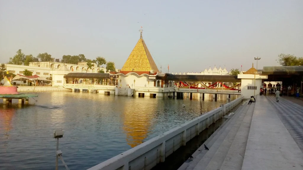The golden shikhara dome of Devi Talab Mandir situated in the middle of its sacred water tank, a spiritual landmark and one of the top religious places to visit in Jalandhar, Punjab.
