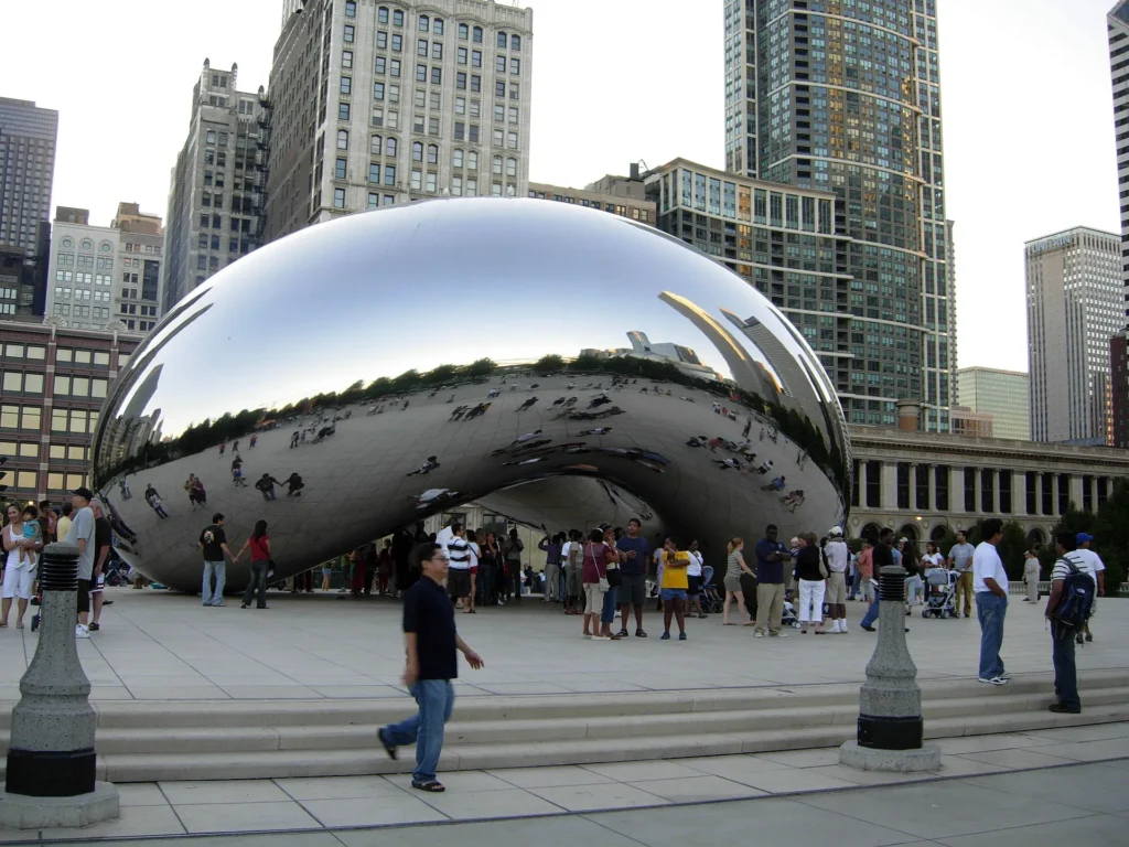 Tourists taking photos at Cloud Gate in Millennium Park during a sunny day, highlighting one of the top things to do in Chicago for first-time visitors.